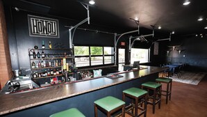 A bar area with stools, a shelf of bottles, and a sign reading "HOWL". - Hotel LaBonte (Douglas)