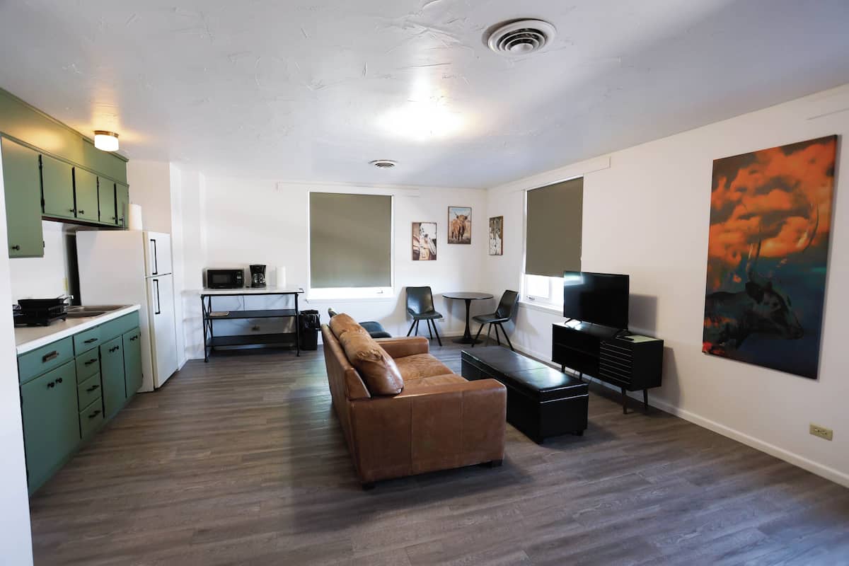 A modern living space with a sofa, a dining table, a TV, and artwork on the walls.