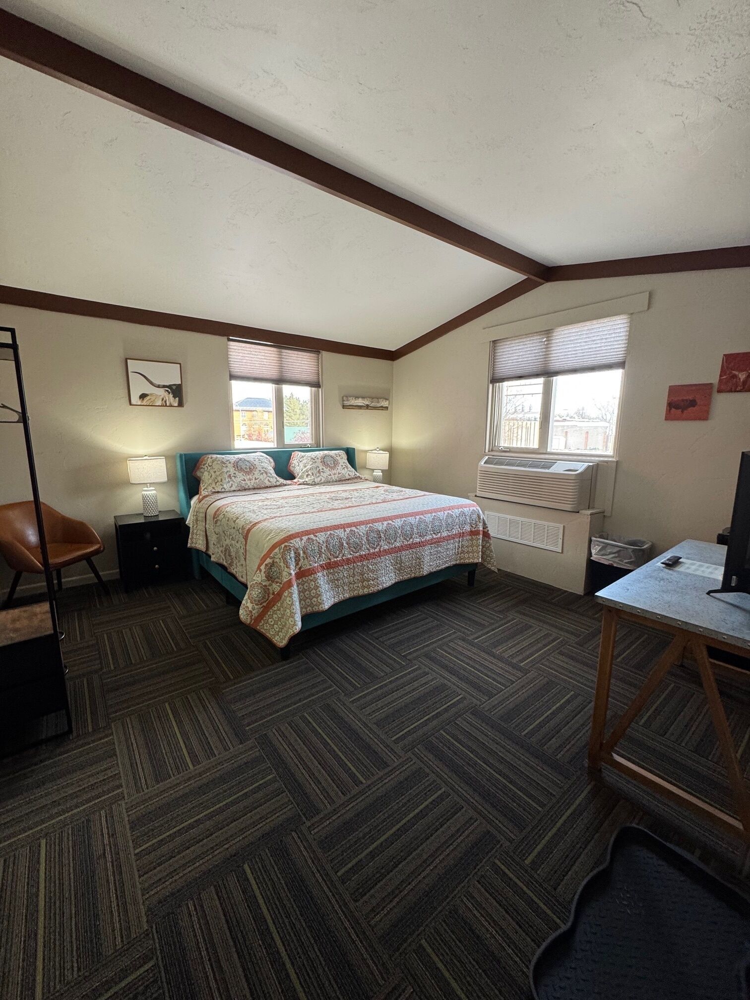 A bedroom with a bed, bedside tables, a desk, and a window.