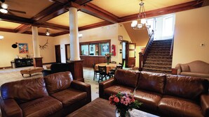 A spacious living room with leather sofas, a wooden coffee table, and a staircase leading to an upper floor. - Hotel LaBonte (Douglas)