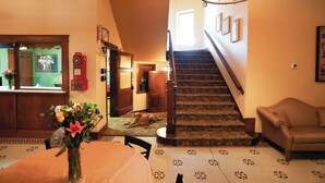 A staircase with a patterned carpet, a wooden chair, and a table with a vase of flowers. - Hotel LaBonte (Douglas)