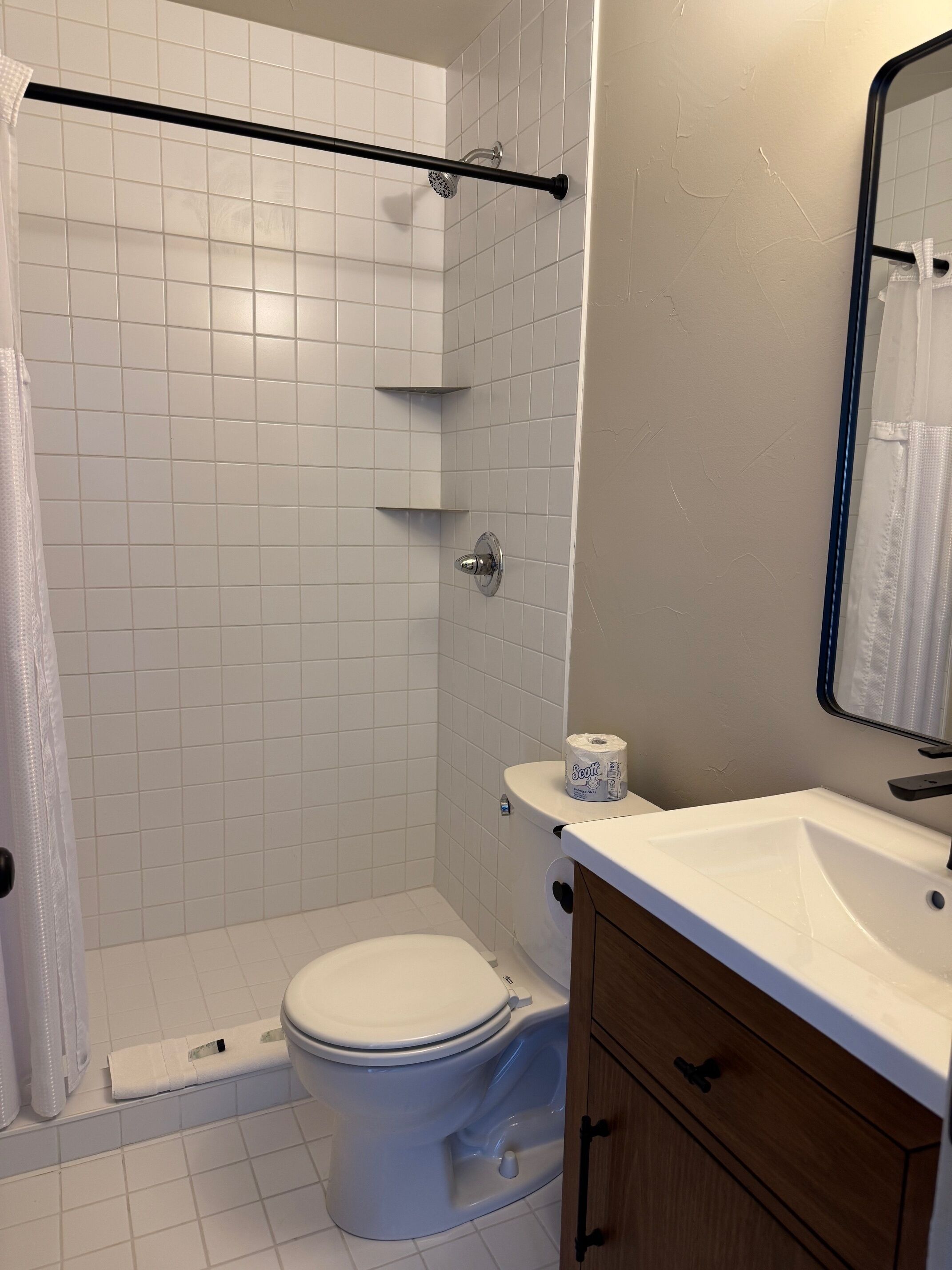 Een badkamer met een douche, toilet en wastafel.