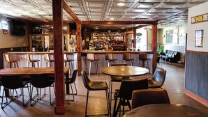 A bar area with wooden furniture, a bar counter, and various bottles. - Hotel LaBonte (Douglas)