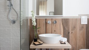 Une salle de bain moderne avec un grand lavabo blanc, un mur recouvert de panneaux en bois et une cabine de douche en verre.
