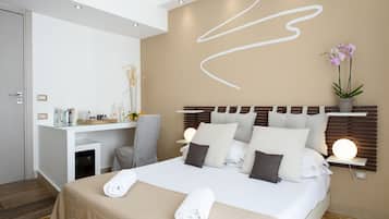 Une chambre d’hôtel moderne avec un lit bien fait, un bureau avec une chaise et une table de chevet avec une lampe.