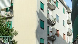 Un immeuble à plusieurs étages doté de balcons, une rue devant et des voitures garées.