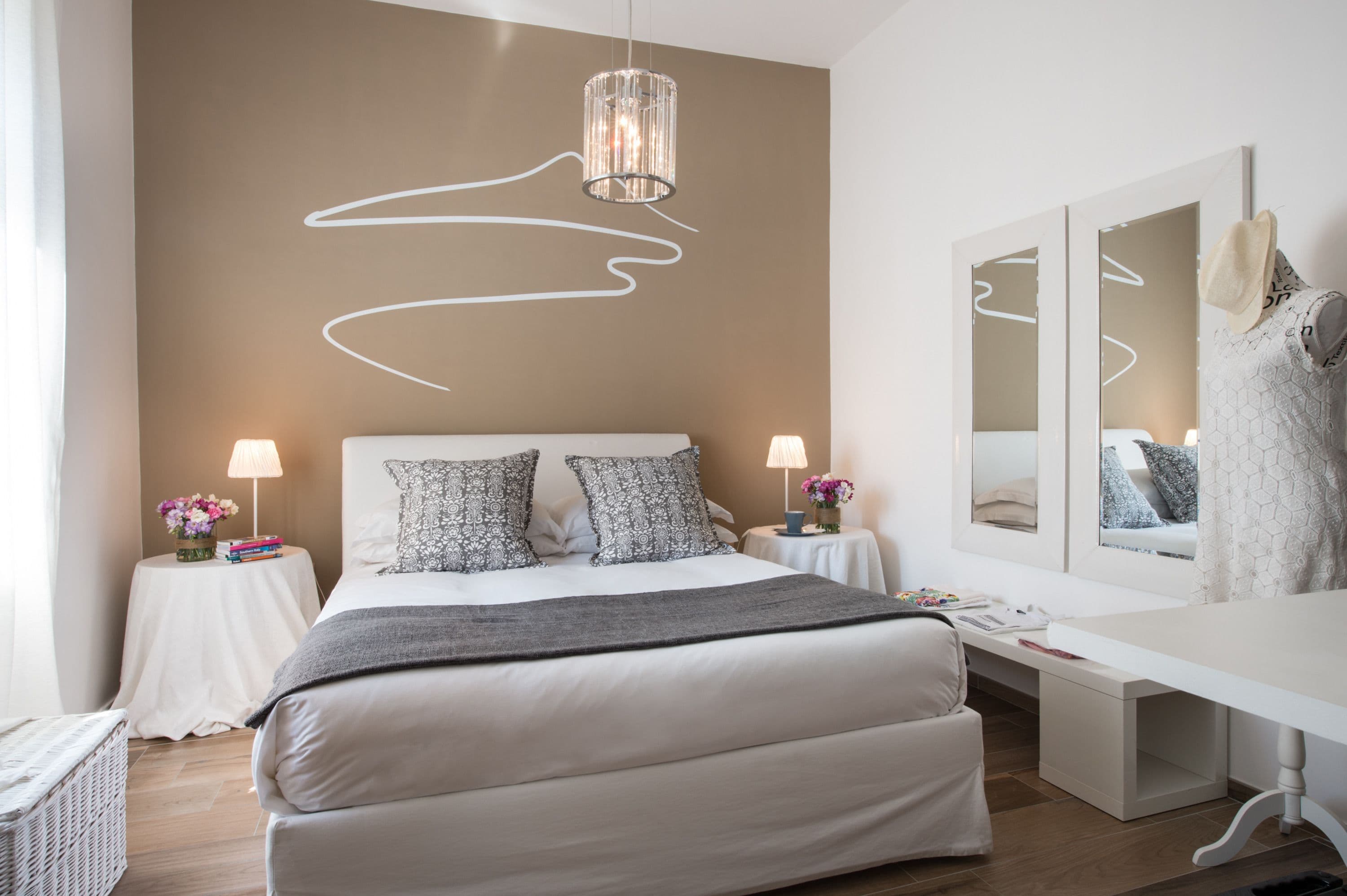 Un dormitorio moderno con una cama grande, mesitas de noche, un escritorio y un espejo.