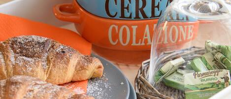 A breakfast tray with croissants, a bowl of cereal, and a basket of cheese.