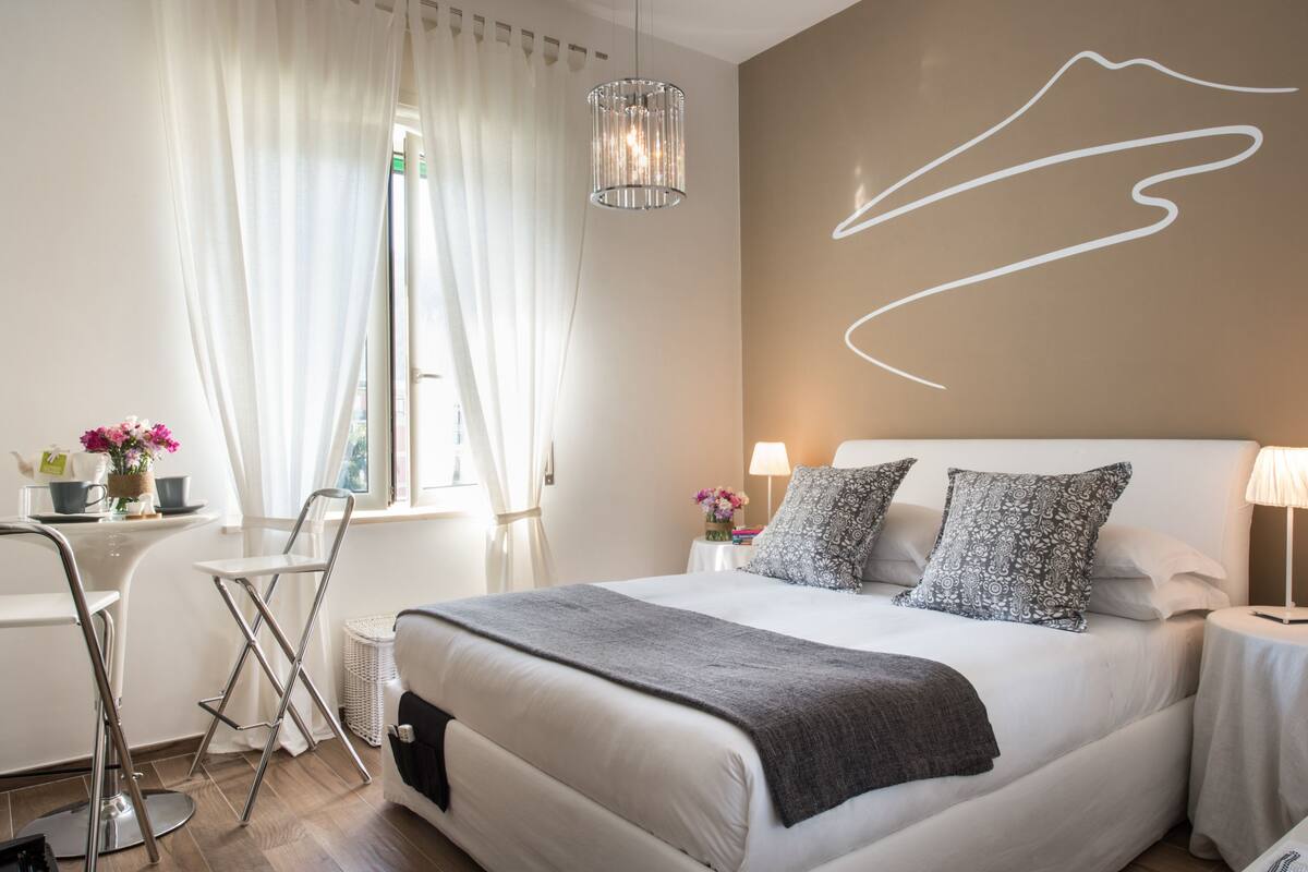 Une chambre d’hôtel moderne avec un grand lit, un bureau avec une chaise, une lampe et un élément décoratif mural.