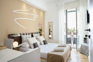 Ein modernes Hotelzimmer mit einem großen Bett, Nachttischen, einem Schreibtisch und einem Balkon mit Gartenmöbeln.