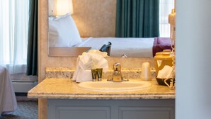 Ett hotellbadrum med handfat, spegel och lampor ovanför spegeln.