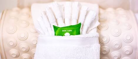 Una toalla blanca con una etiqueta verde sobre un cojín beige con textura.