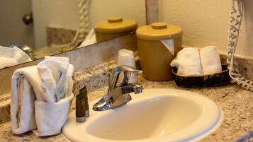 A bathroom sink with a mirror, a towel dispenser, and a basket of towels.