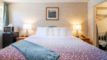 Une chambre d’hôtel comprenant un lit, deux lampes de chevet, un bureau avec une lampe, un four à micro-ondes et un porte-manteau.