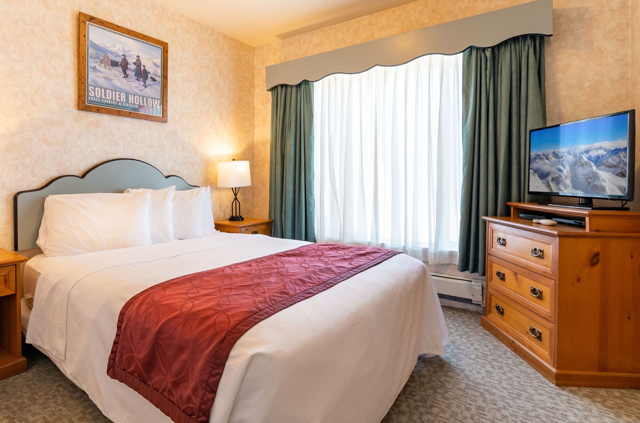 A hotel room with a large bed, a television, a dresser, and a window with curtains.