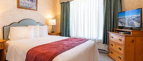 A hotel room with a large bed, a television, a dresser, and a window with curtains.