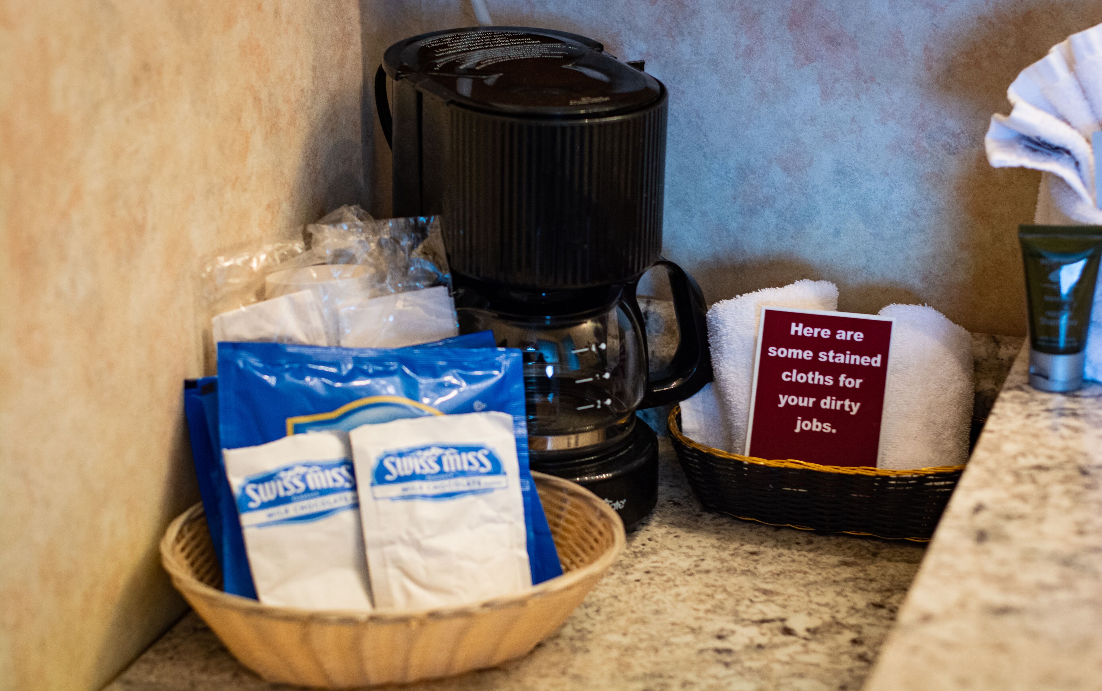 A coffee maker, a basket with some items, and a sign with text.