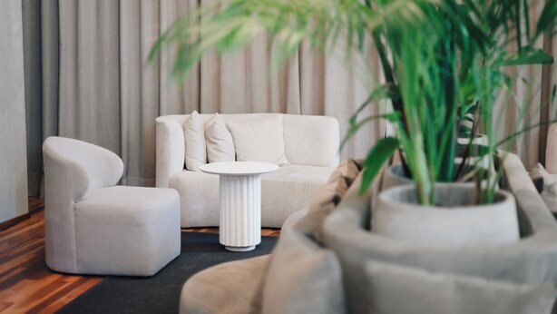 Una sala de estar moderna con un sofá, un reposapiés y una mesa de centro redonda.