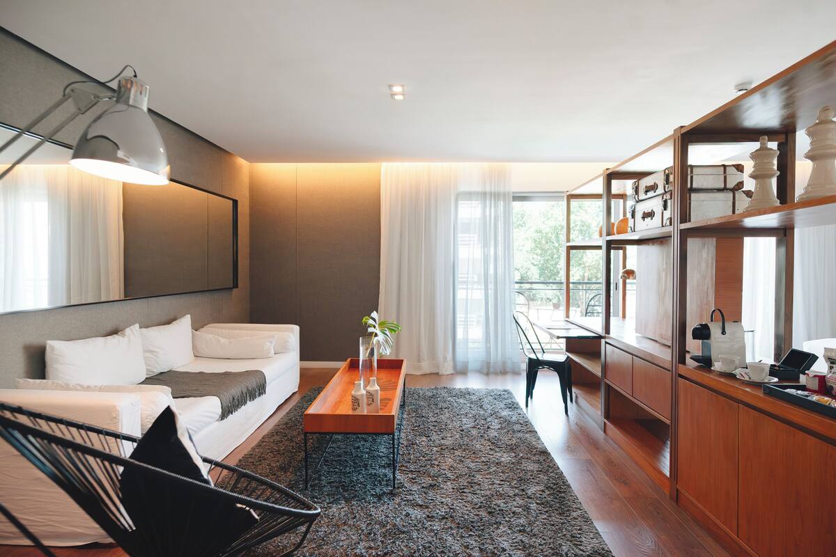 A modern living room with a sofa, a coffee table, a desk, and a bookshelf.