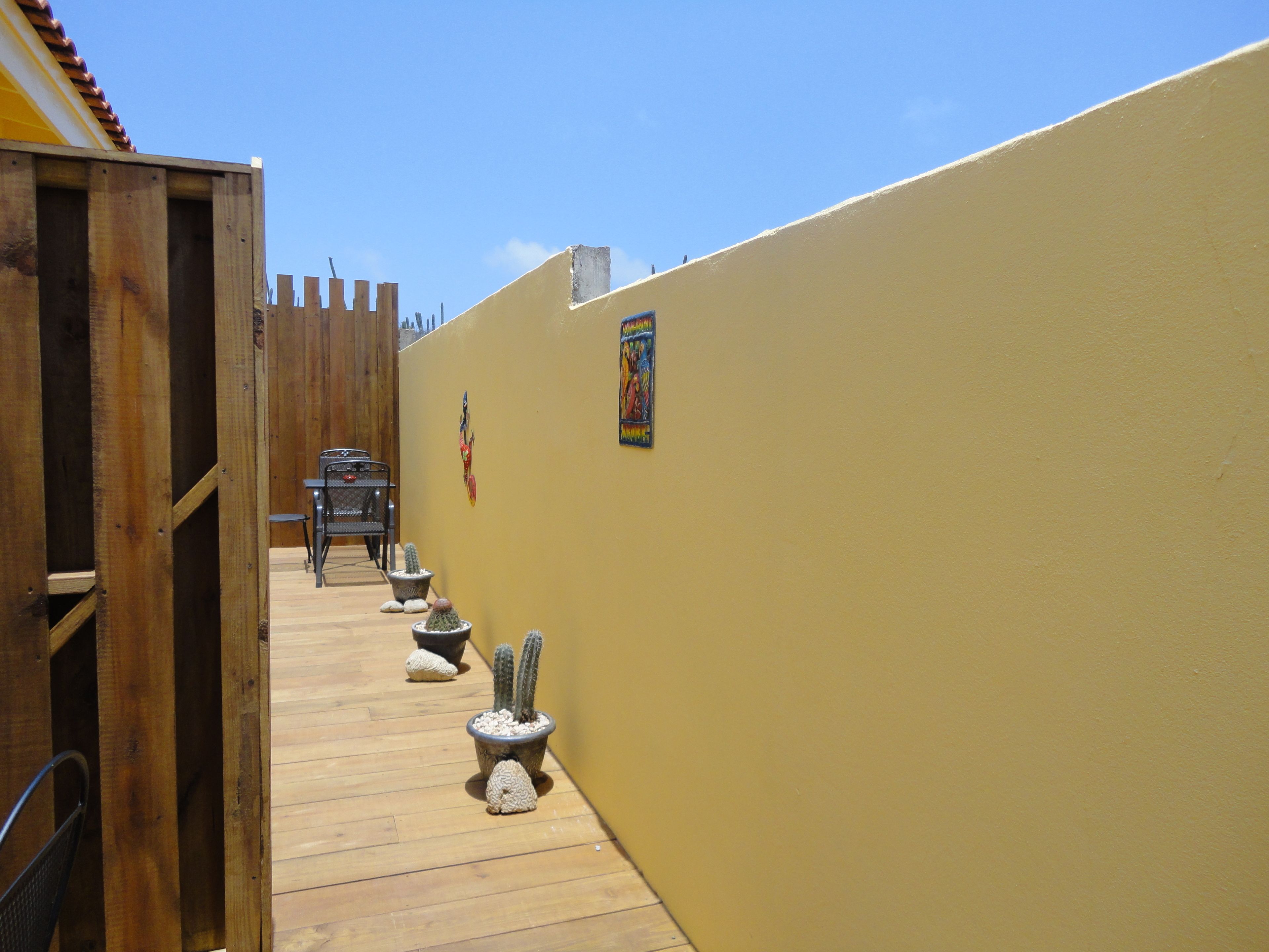 Un étroit couloir en bois, avec un mur jaune, qui mène à un espace détente comprenant une table et des chaises.