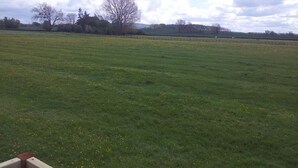 A large open field with a fence in the foreground and trees in the background. - Shepherds Lodge (Worcester)
