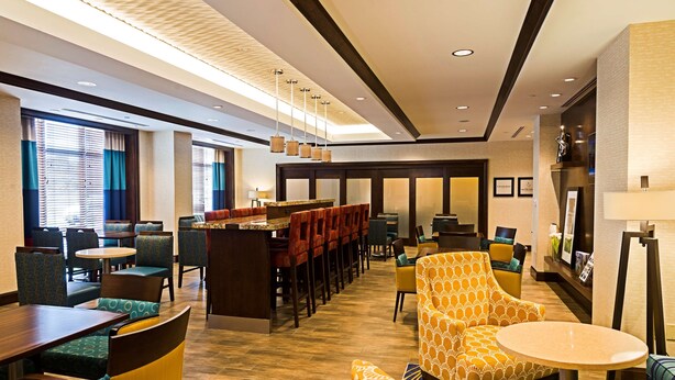 Una hall d'albergo con angolo bar, posti a sedere e reception.