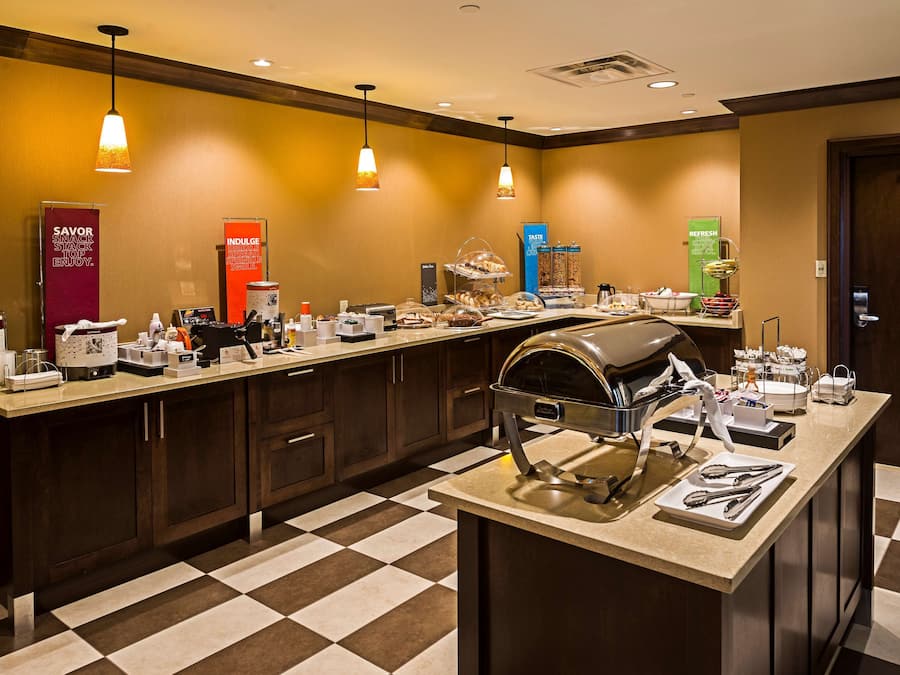 Un'area colazione in hotel con un buffet, inclusa una postazione caffè, diversi articoli alimentari e un distributore automatico di bevande.