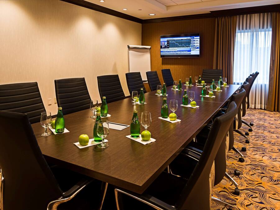 A conference room with a long table, chairs, and a screen displaying a presentation.