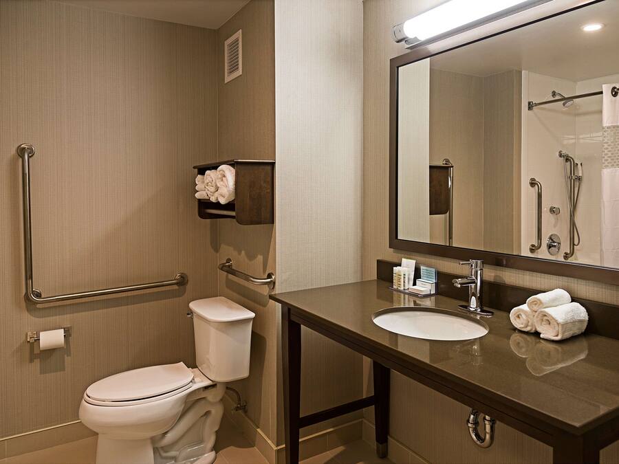 A bathroom with a toilet, sink, mirror, and towel rack.