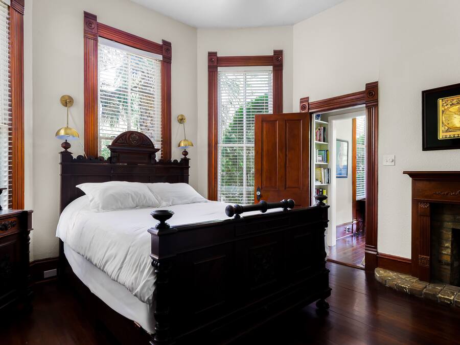 Una camera da letto tradizionale con un letto a baldacchino, pavimento in legno e un camino.