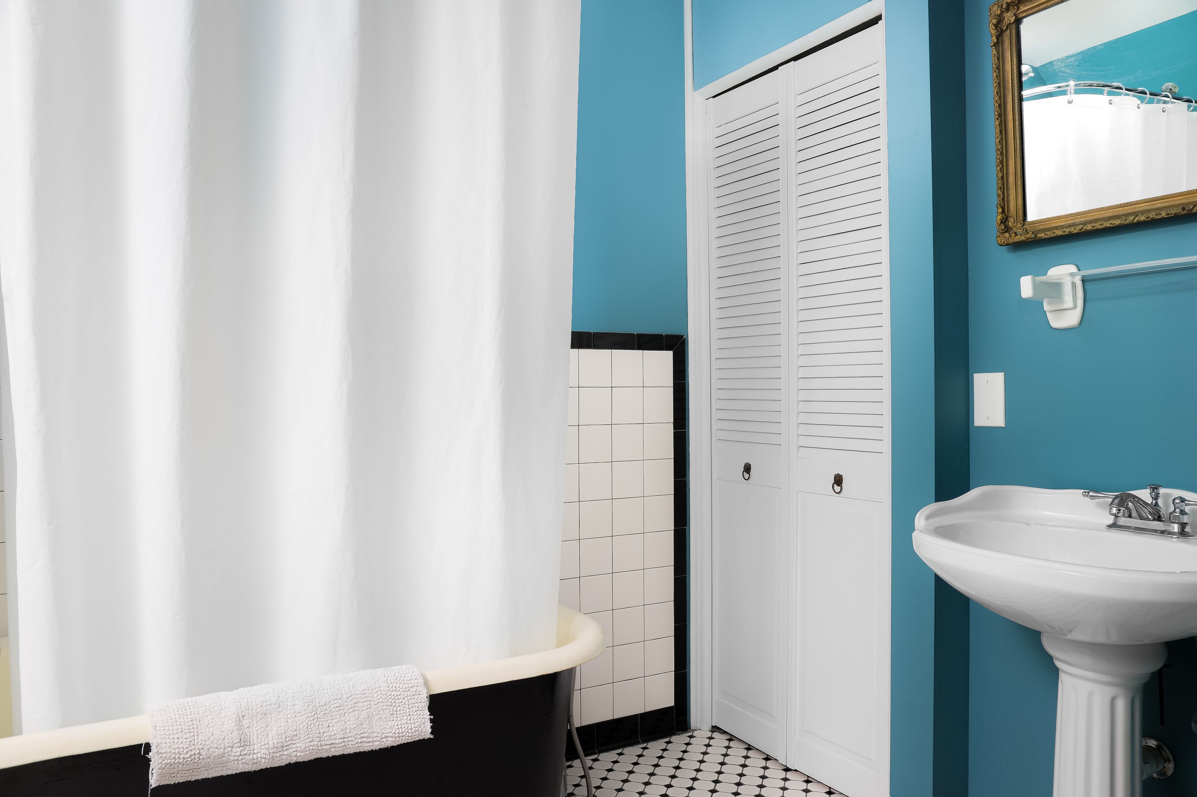 A bathroom with a bathtub, a white sink, and a mirror on a blue wall.