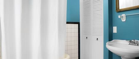 A bathroom with a bathtub, a white sink, and a mirror on a blue wall.