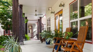 A covered porch with wooden chairs and potted plants, a staircase, and a ceiling fan. - Brava House Bed and Breakfast (Austin)