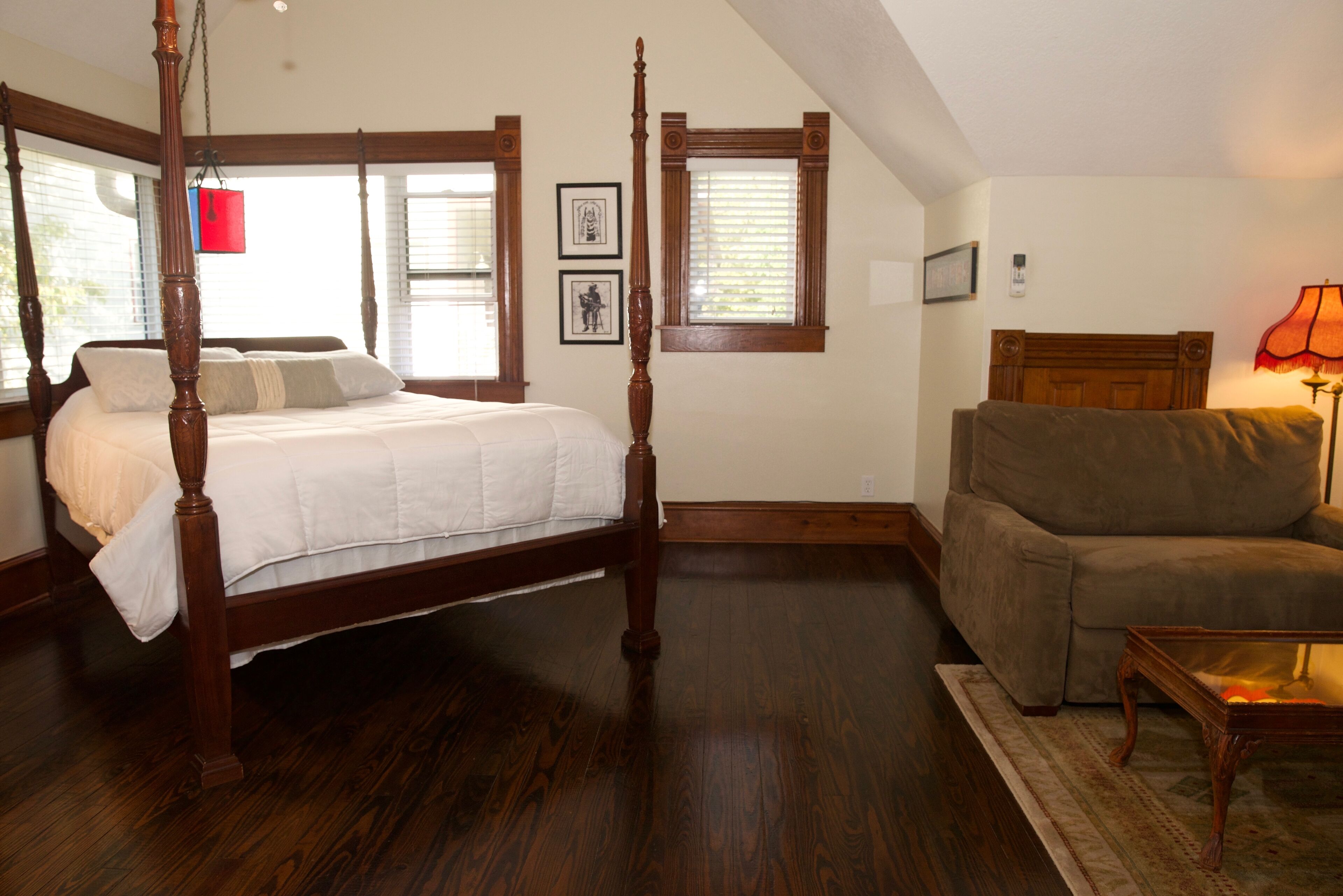 A bedroom with a four-poster bed, a sofa, and a small table.