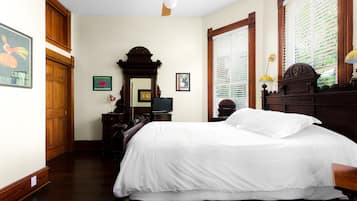 A hotel room with a large bed, wooden furniture, a ceiling fan, and a television.