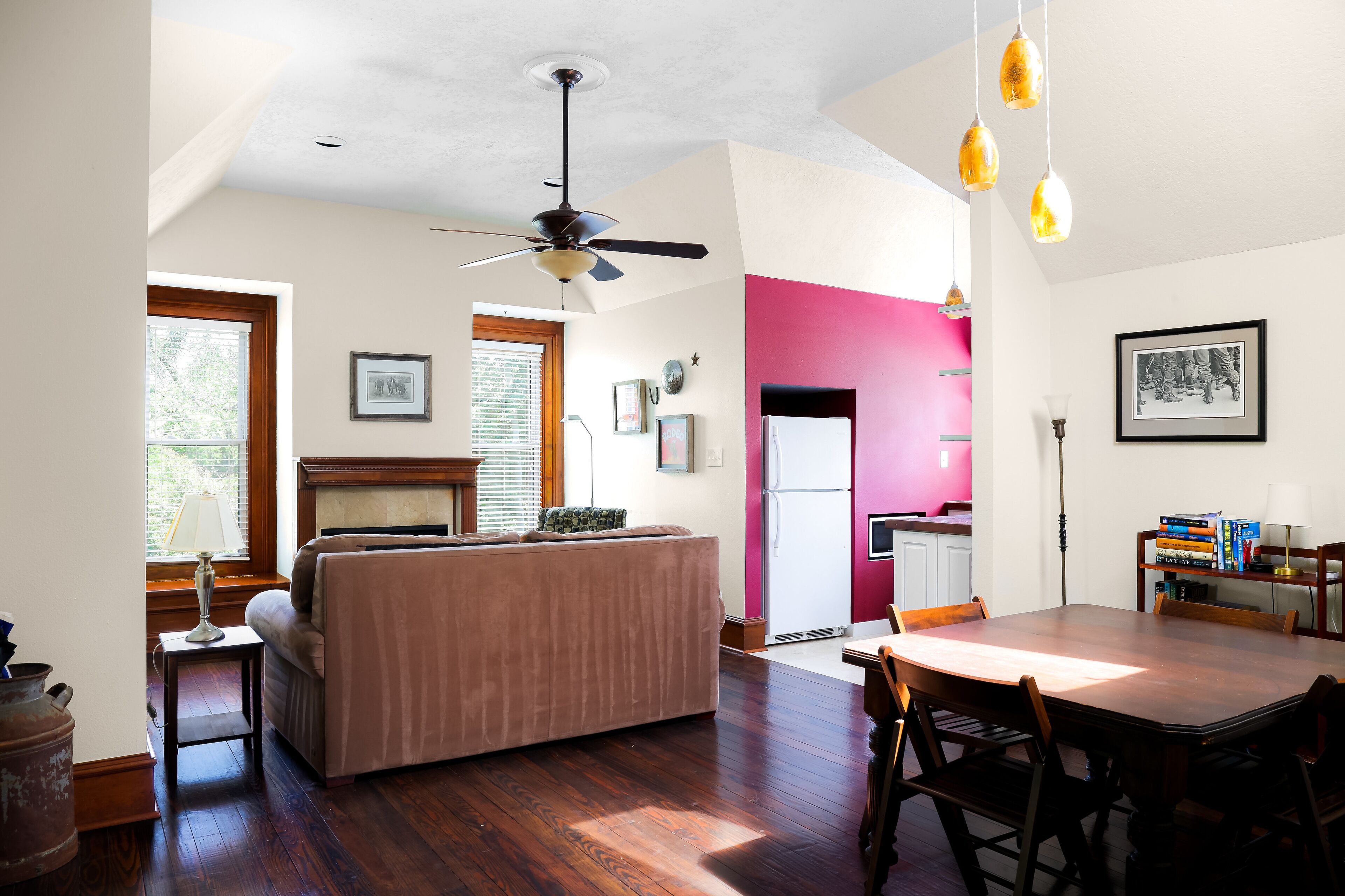 A spacious living area with a large wooden dining table, a sofa, and a ceiling fan.