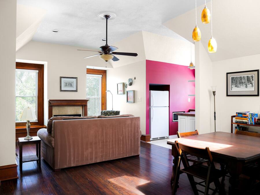A spacious living area with a large wooden dining table, a sofa, and a ceiling fan.