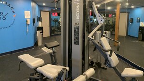 A gym with exercise equipment, a wall-mounted phone, and a mirror reflecting the equipment. - Longhollow Point Inn Studio 1105 (Galena)
