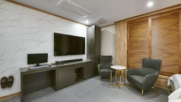 Una sala de estar moderna con un televisor de pantalla plana, sillones grises, una mesita redonda y un mueble empotrado para entretenimiento.