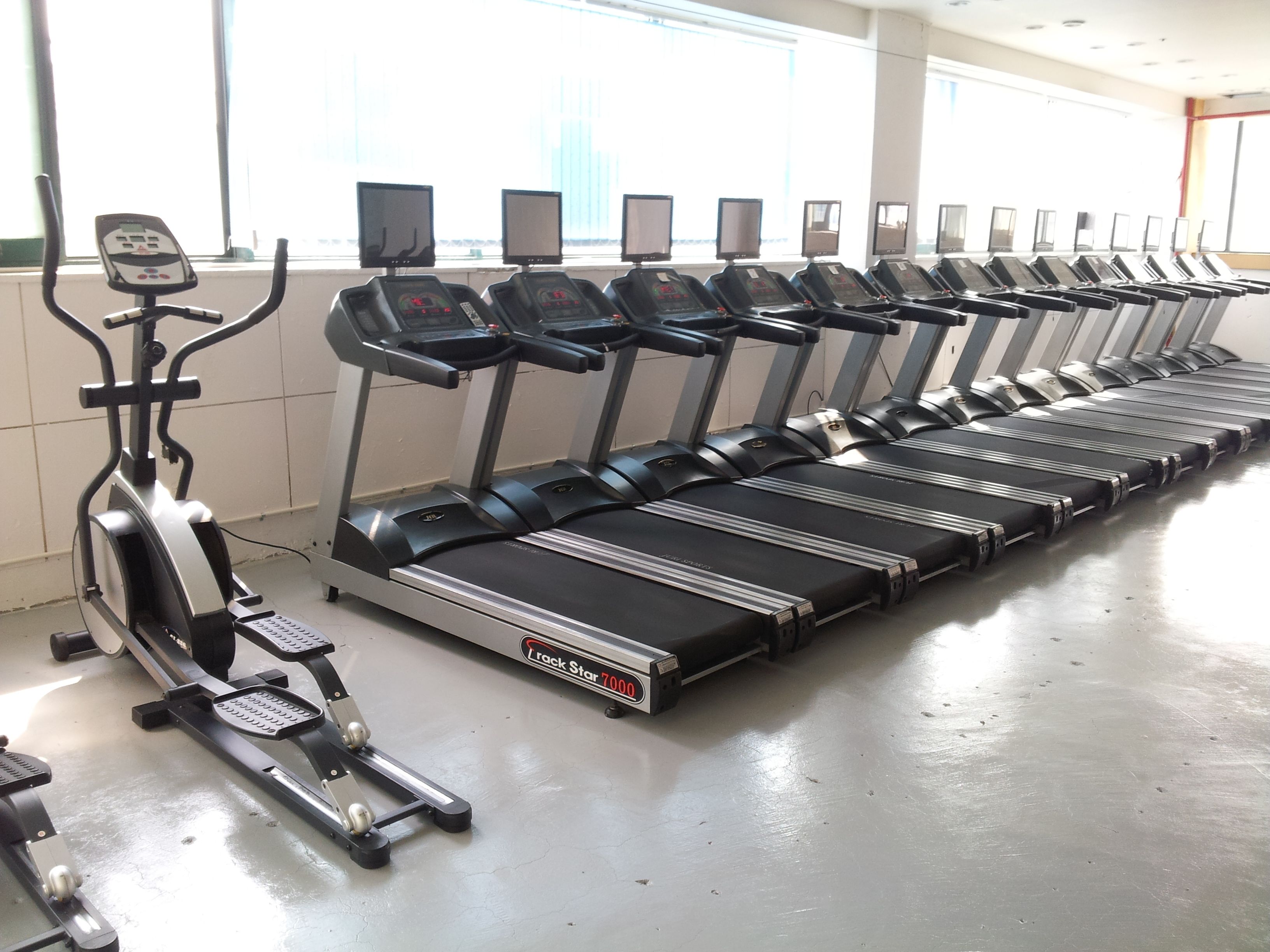 Varias cintas de correr en un gimnasio, con un panel de control a la izquierda.