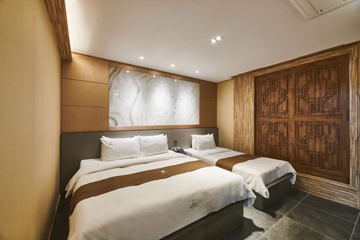 A hotel room with two beds, a large decorative wall, and a traditional wooden door.
