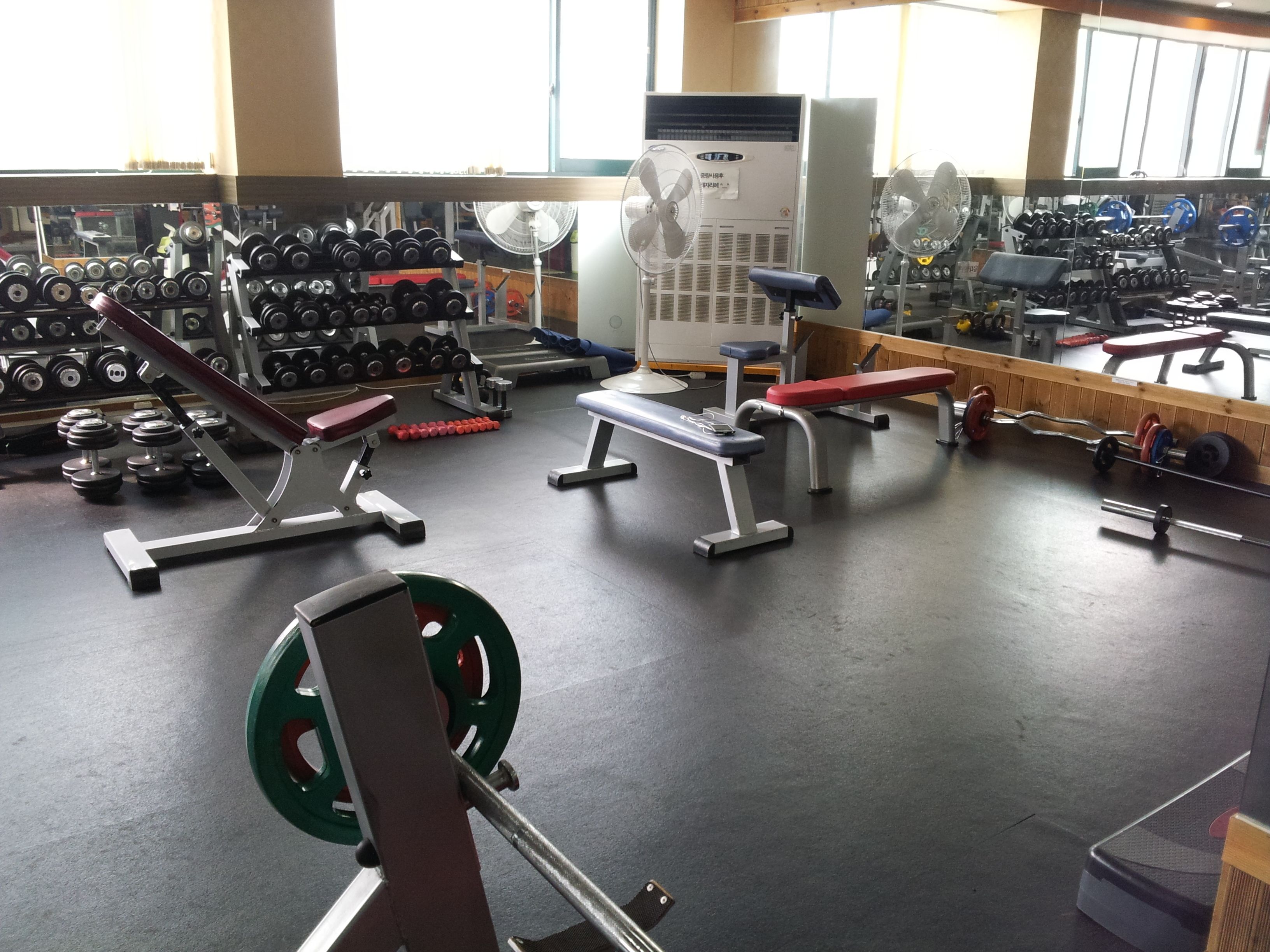 Une salle de sport équipée de matériel de musculation, de bancs et d’haltères.