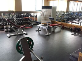 A gym with weightlifting equipment, benches, and dumbbells.