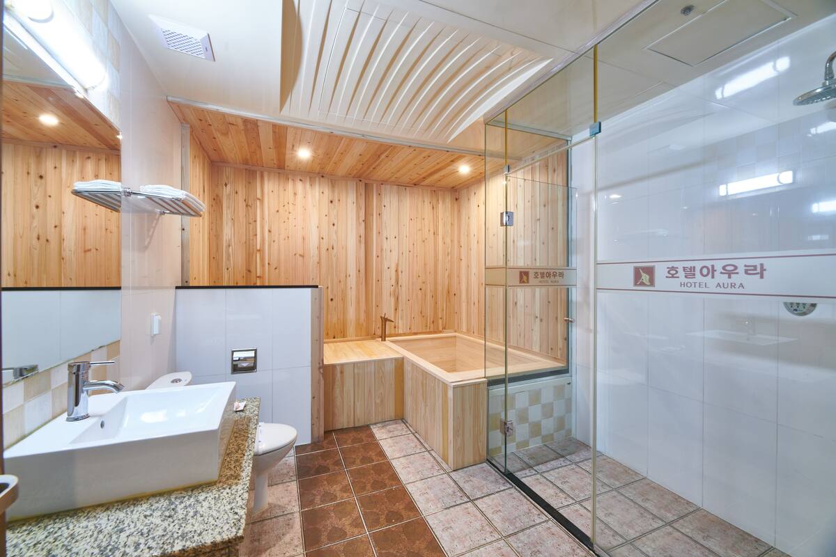 A modern bathroom with a wooden panel wall, a glass-enclosed shower, a freestanding bathtub, and a sink with a granite countertop.
