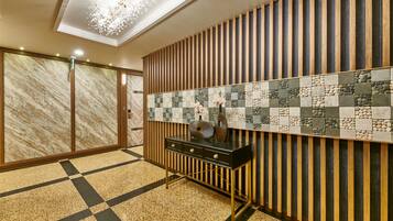 A modern interior with a checkered floor, a wooden panel wall, and a black console table with decorative items.