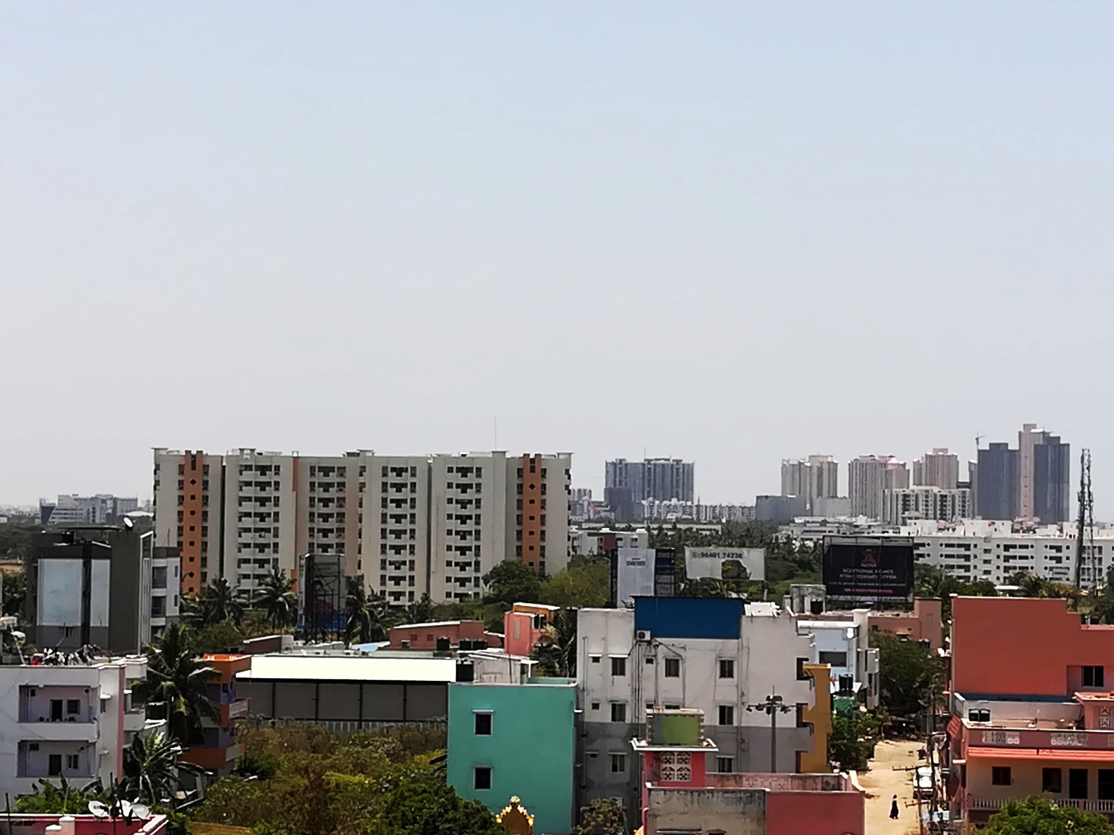 A cityscape with multi-story residential buildings, some with balconies, and a variety of building heights and designs.