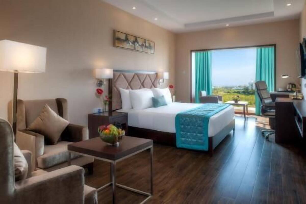 Une chambre d’hôtel équipée d’un lit, d’un bureau, d’une chaise, d’un canapé et offrant une vue sur l’extérieur.