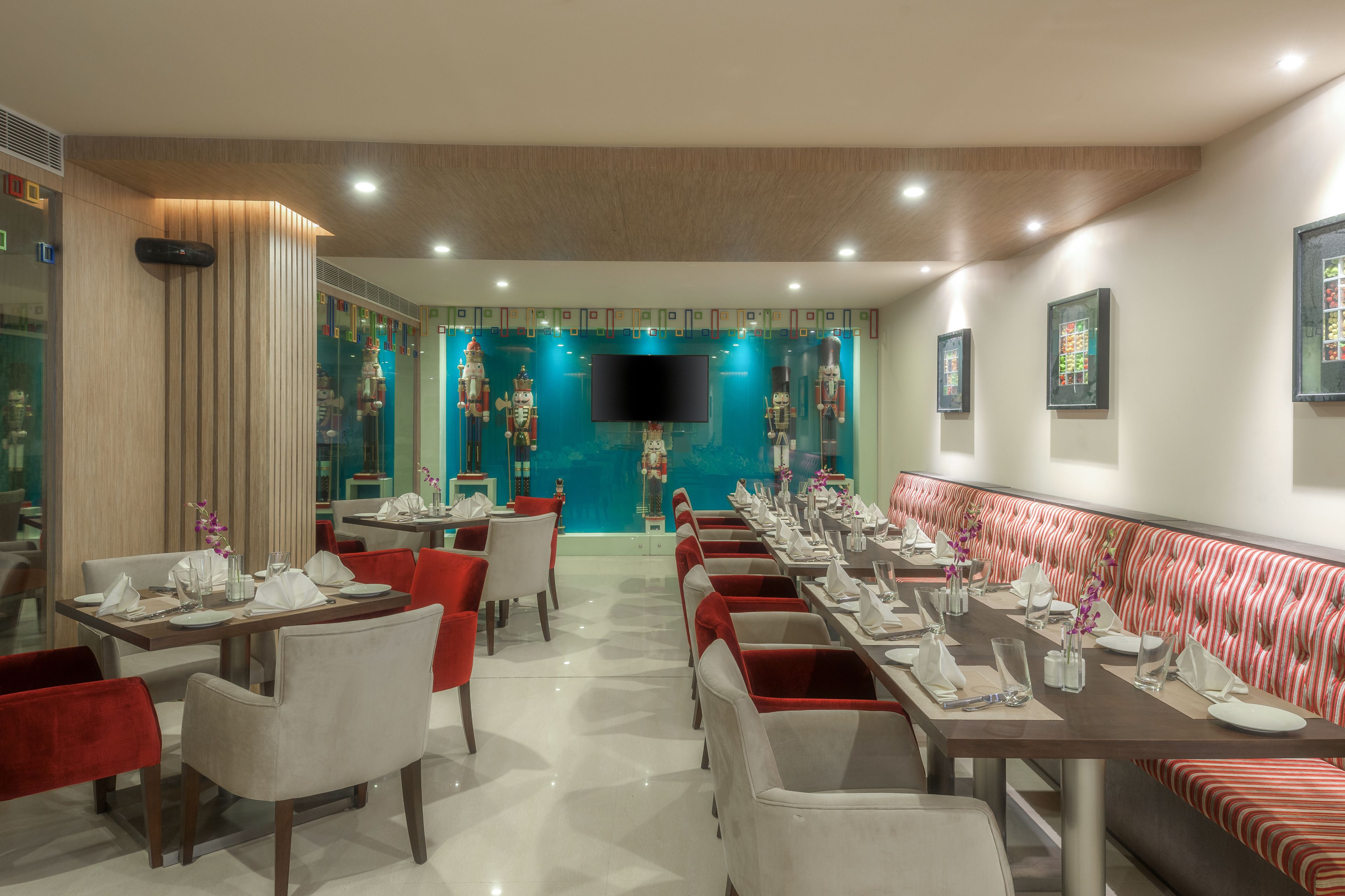 A restaurant with a long dining table, red and white chairs, and a striped bench.