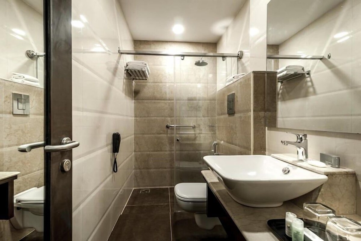 Un baño moderno con ducha envuelta en vidrio, un lavamanos blanco y un inodoro.