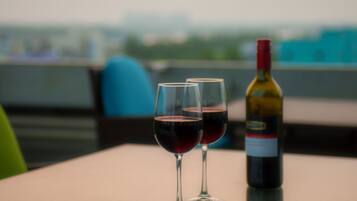 Dos copas de vino y una botella sobre una mesa, con vistas a la ciudad.